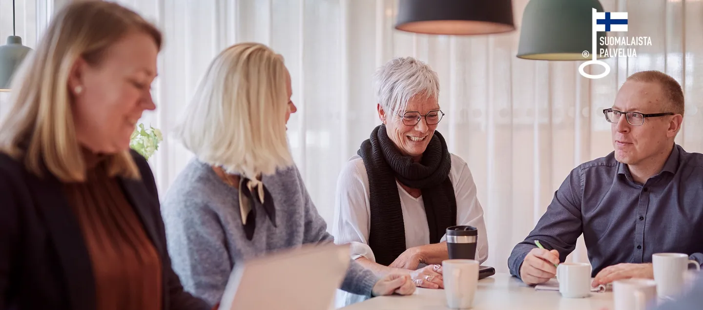 ryhmä hymyileviä, eri-ikäisiä aikuisia oppimistilanteessa