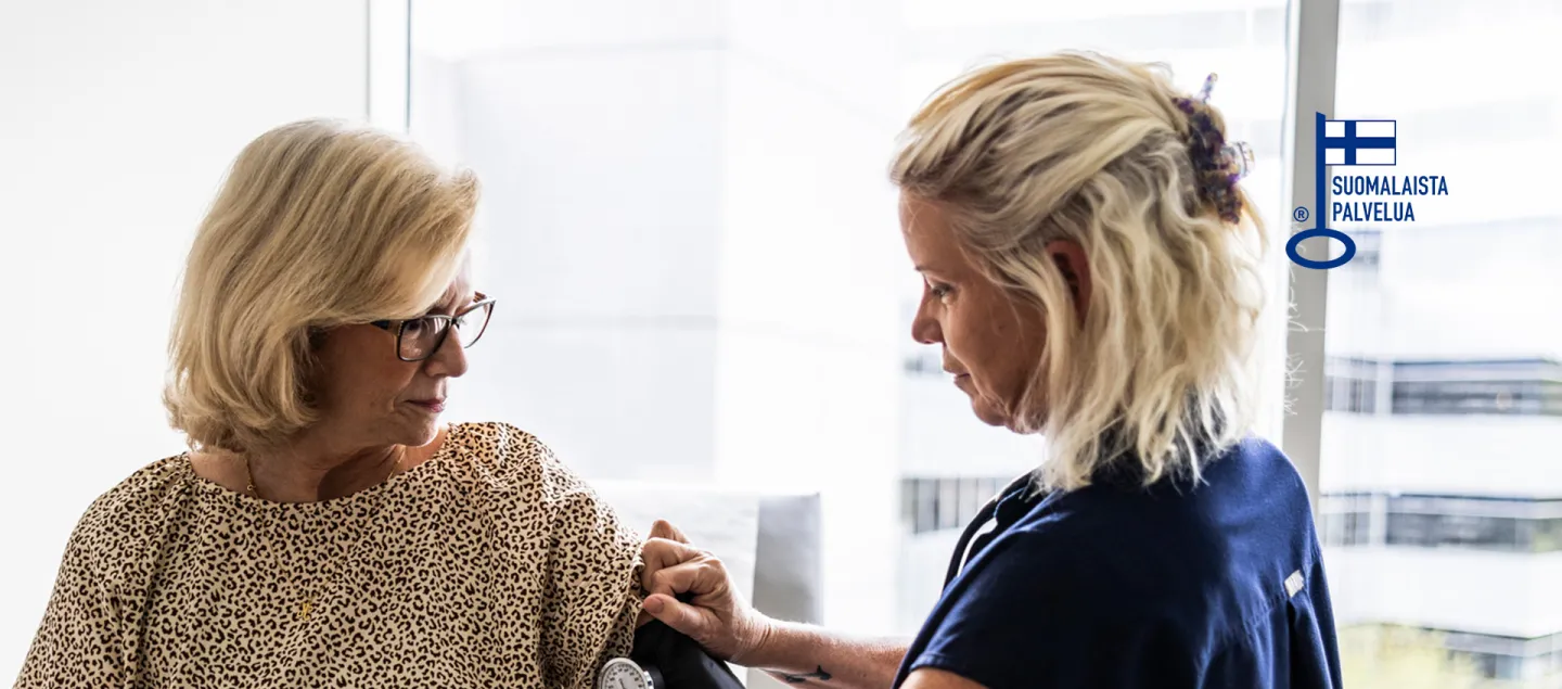 Hoitaja asettaa verenpainemittarin mansettia asiakkaan käsivarteen.