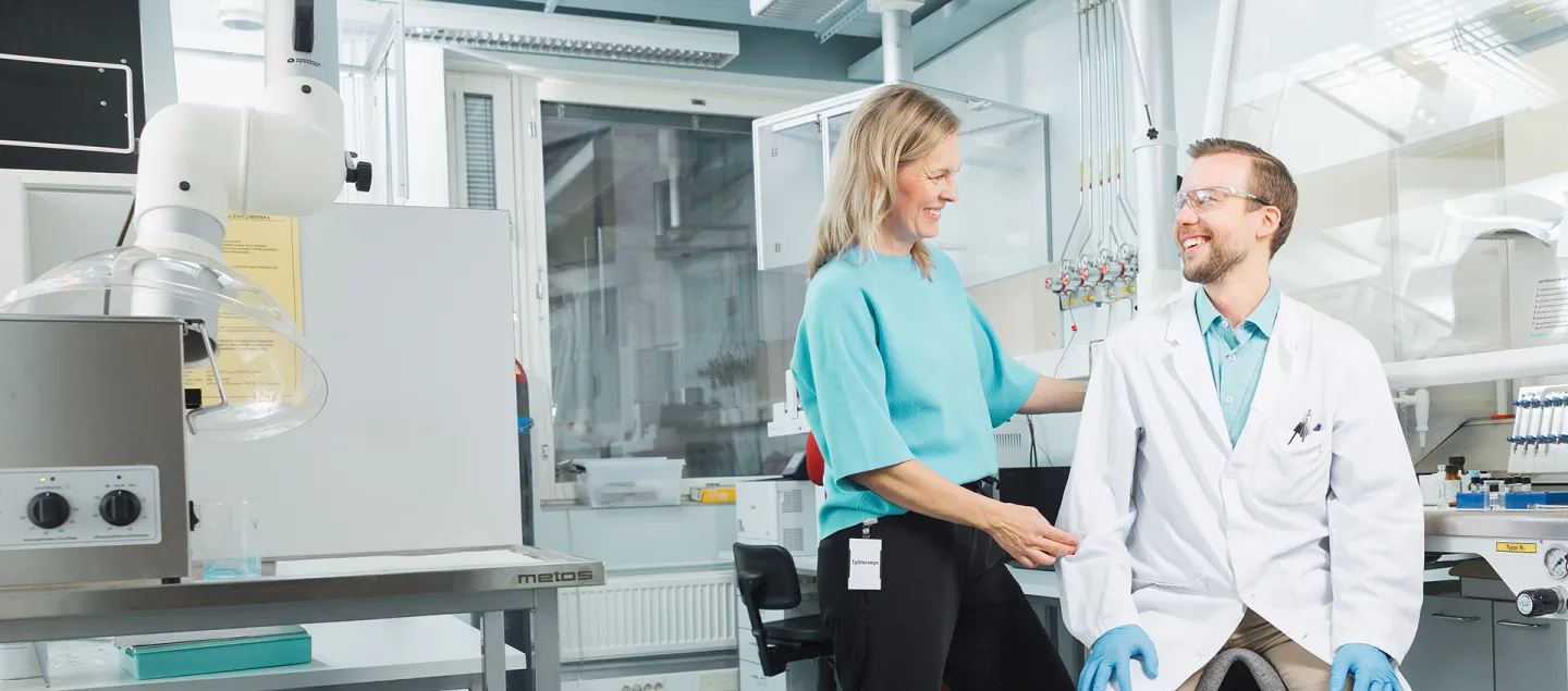 Fysioterapeutti tarkistaa laboratoriossa työntekijän istuma-asentoa.