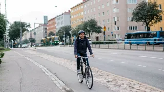 Mies pyöräilee kadulla.