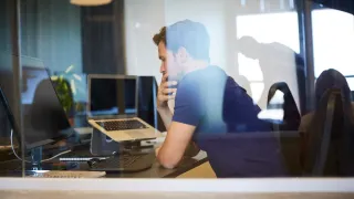 Tutkija tekee töitä toimistossa kannettavalla tietokoneella.