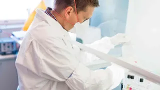 Valkotakkinen mies työskentelee laboratoriossa