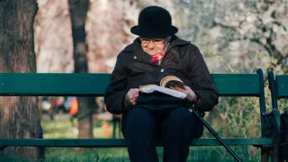kuvituskuva vanhus lukee kirjaa puistossa