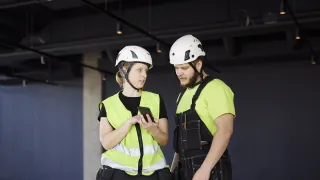 kuvituskuva: rakennusalan työntekijöitä puhelin kädessä