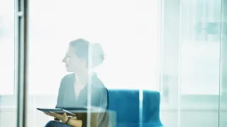 kuvituskuva: nainen toimistossa lasiseinän takana