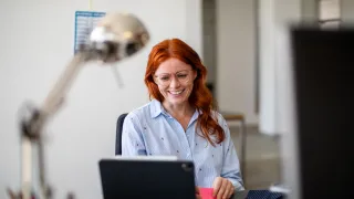 Henkilö katsoo kannettavaa tietokonetta ja hymyilee. 