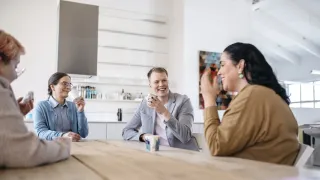 Neljä ihmistä juttelee pöydän äärellä.