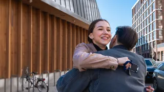 Kaksi henkilöä halaa toisiaan kadulla, toisella on kädessään henkilökortti