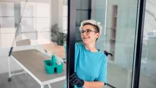 Nainen pesee ikkunoita toimistotilassa