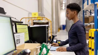 Varastotyöntekijä katsoo tietokoneen näyttöä varastoympäristössä. 