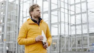 Mies kävelee kannettava tietokone kainalossa ja mietteliäs ilme kasvoilla