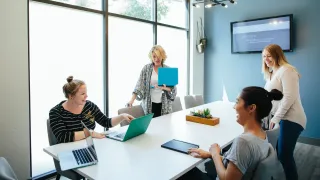 Hymyilevät naiset valmistautuvat palaveriin kokoushuoneessa