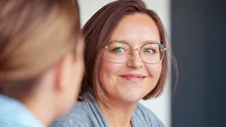 Lähikuva kollegalleen hymyilevästä naisesta