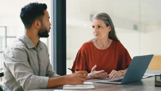 Nuori mies ja vanhempi nainen keskustelevat toimistolla