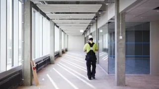 Takaa päin otettu kuva työmiehestä, joka kävelee rakennustyömaalla