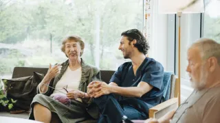 Hoitaja keskustelee ikäihmisten kanssa.