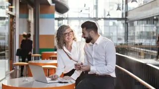 Hymyilevät kollegat keskustelemassa aulassa