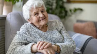 Vanha nainen istuu ja hymyilee