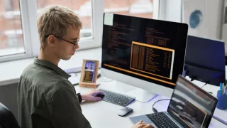 Työntekijä tutkii näyttöpäätettään silmälasit päässä.