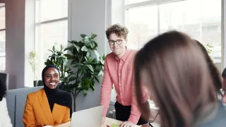 Kolme työntekijää kohtaa toimistopöydän äärellä.