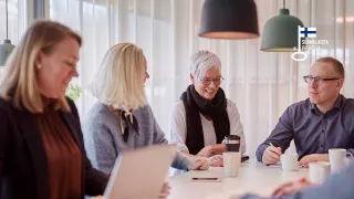 ryhmä hymyileviä, eri-ikäisiä aikuisia oppimistilanteessa