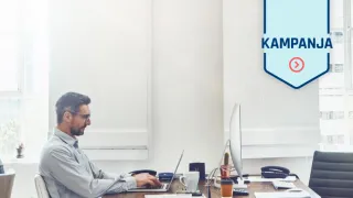 Mies työskentelee kannettavalla tietokoneella pöydän ääressä