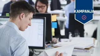 Mies selaa paperinippua työpöydän ääressä toimistossa