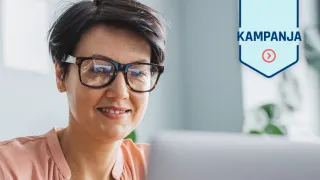 Hymyilevä nainen kannettavan tietokoneen ääressä