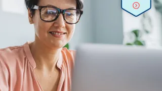 Hymyilevä nainen kannettavan tietokoneen ääressä