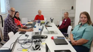 Ihmisiä istuu kokouksessa pöydän äärellä.