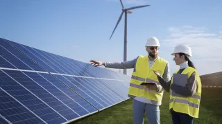 Kaksi työntekijää keskustelee aurinkopaneelien edessä. 