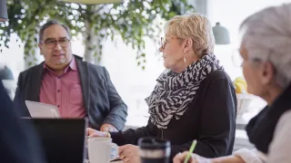 Toimihenkilöt istuvat työpöydän ääressä.