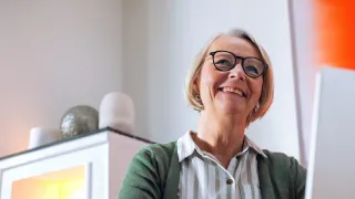 Hymyilevä henkilö tietokoneen äärellä koulutuksessa.