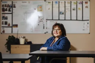 Katja Saarinen istuu pöydän ääressä ja katsoo kameraan. 