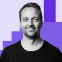 Mies katsoo kameraan ja on valokuvattavana sinistä taustaa vasten