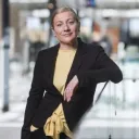 Henkilö katsoo kameraan ja on kuvattavana toimistotilassa.