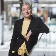 Henkilö katsoo kameraan ja on kuvattavana toimistotilassa.